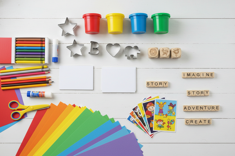 Overhead flat lay of creative materials: playdough, cookie cutters, story creation tools, art supplies